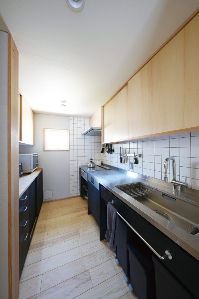 黒で塗装した造作キッチン。白いタイルとのコントラストが素敵です。シンクやカウンターは掛ける収納ですっきり。