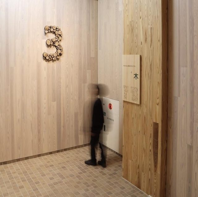 階数表示のサインはワークショップでみんなでつくった木のサイン。 柱・梁の仕上げは多摩産材のクリア塗装仕上げ、その他の壁面は木に白染色で上品な仕上げ