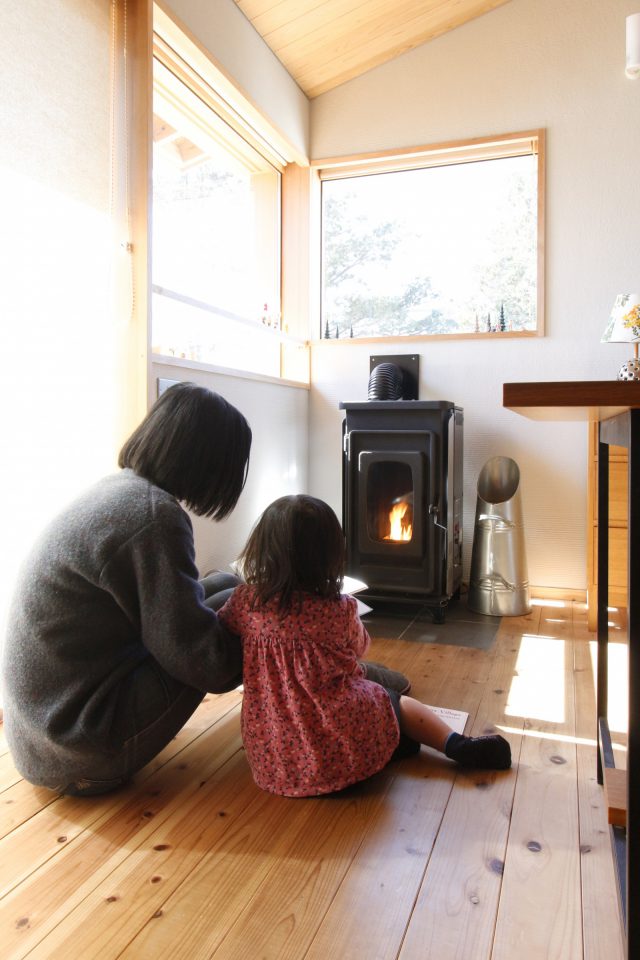 ペレットストーブの前で本を読む親子