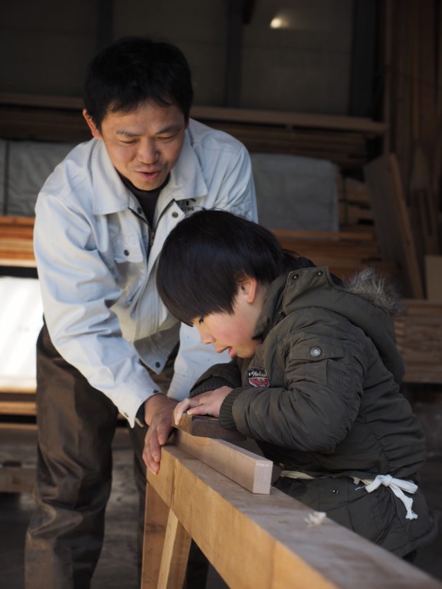 カンナがけ体験。「体ぜんたいで引いていくんだ！がんばれ！」