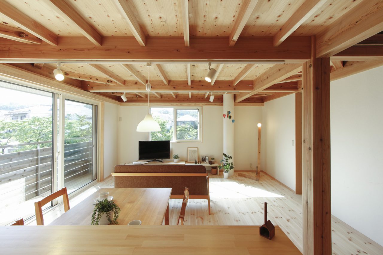 1号棟の二階リビング。写真左が南面で、大きな開口部とバルコニーがあります。窓の外には川沿いの緑が見えて気持ちいい。