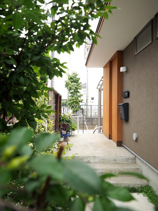 緑の植栽に囲まれたアプローチを通って玄関へ。