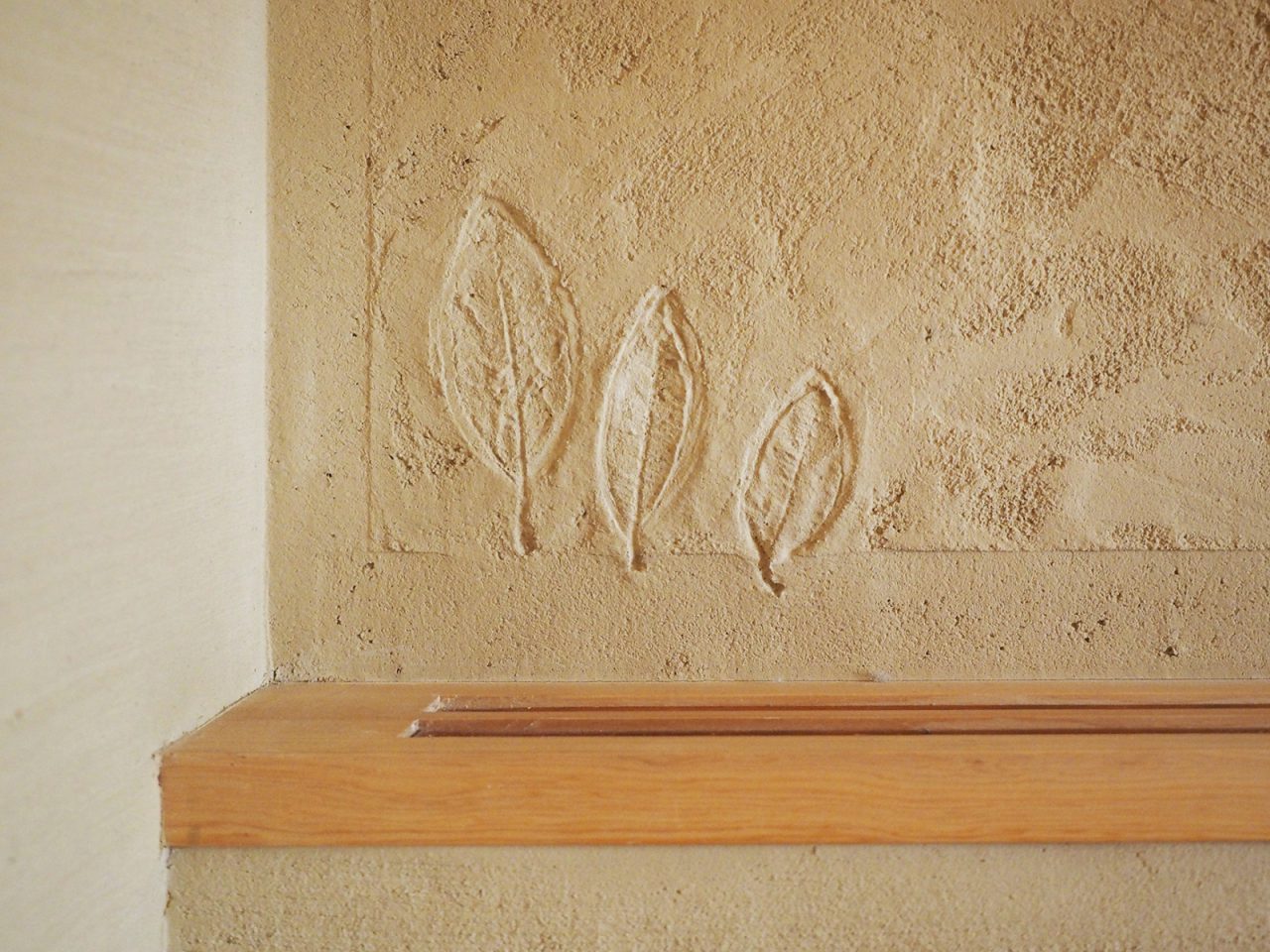 家族で手を加えた葉模様の左官壁
