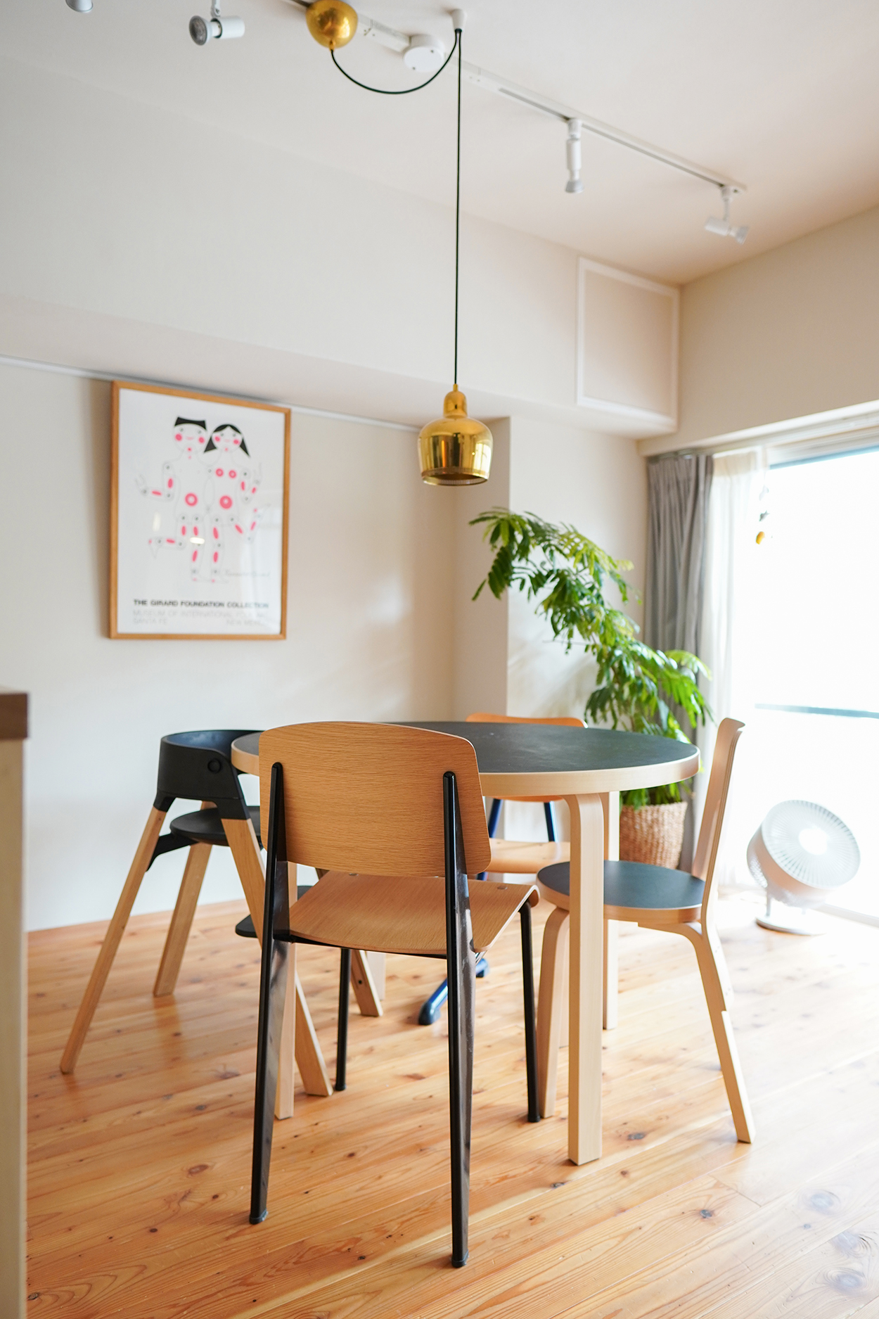 アルヴァ・アアルトがデザインした照明「ゴールデンベル」やこだわりの家具、ポスターが自然素材の空間と調和している。