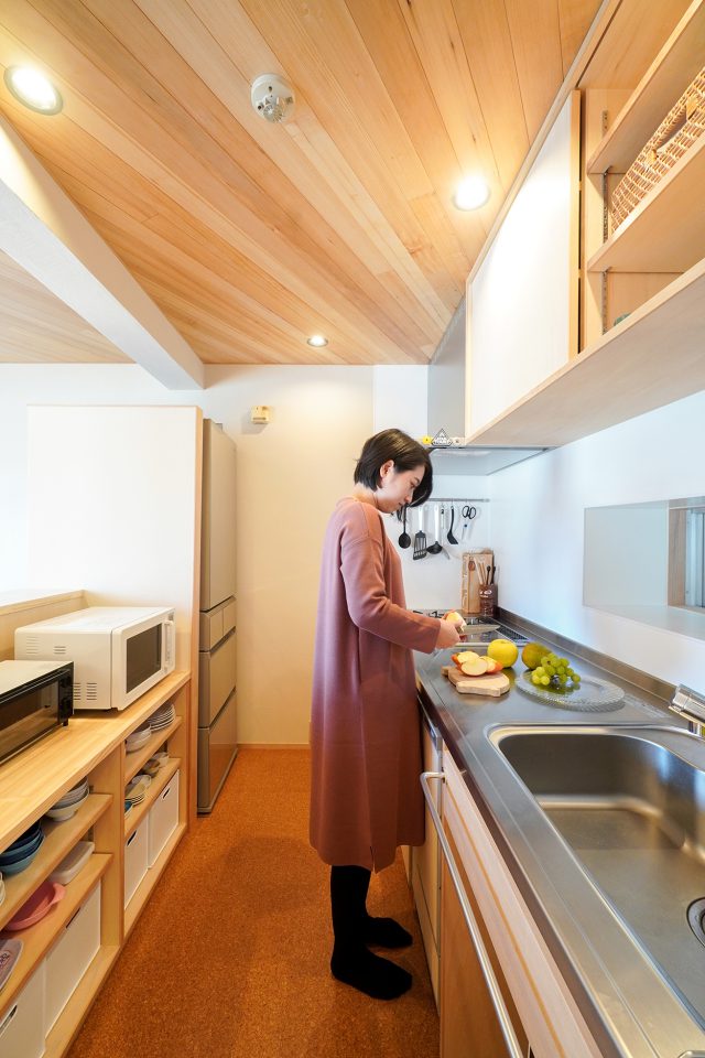 ダイニングから見えない位置に家電が収まる木製の造作キッチン。