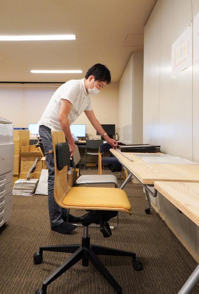 新しい事務所の空間の図面とオフィスチェアの寸法を照らし合わせて確認する設計の松本。