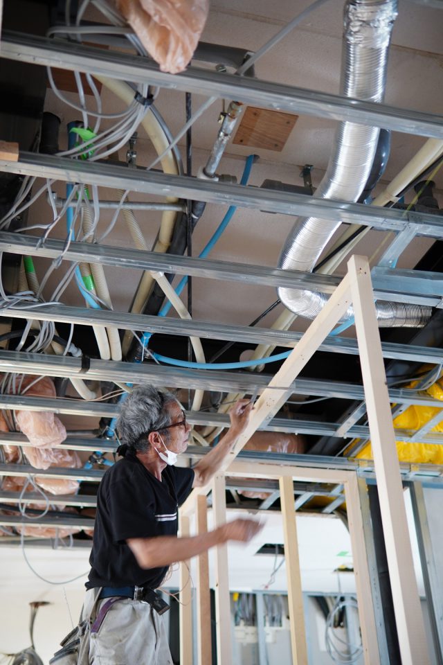 2階天井は一部が剥がされている状態で、3階床下の配管や配線が見えて、オフィスや施設の工事ならではの場面です。