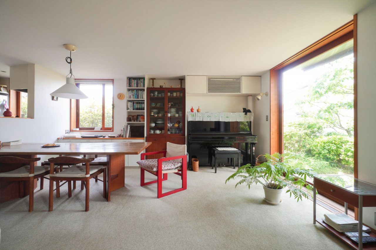 木曾三岳奥村設計所のダイニングテーブルと「はんぺんチェア」は以前の家から約50年も愛用。昌民さんの恩師・吉村順三さんの「たためる椅子」の赤がアクセントに。