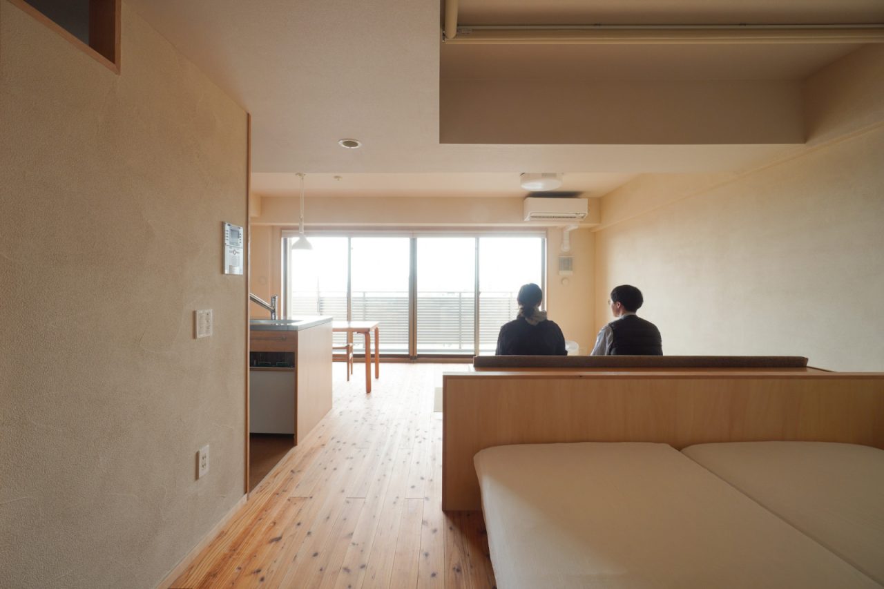 ベッドルームからリビングを望む。廊下の天井高をリビングより低くおさえたことで空間により広がりを感じられるようになりました。ロールスクリーンも段差に隠してすっきりと。