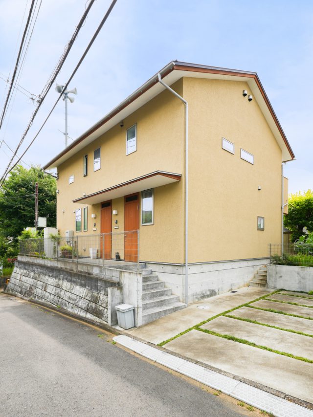 道路側は開口を絞って、シンプルに。 玄関は各世帯ごとに分けられており、２つ並んだ木製扉が可愛らしい外観です。