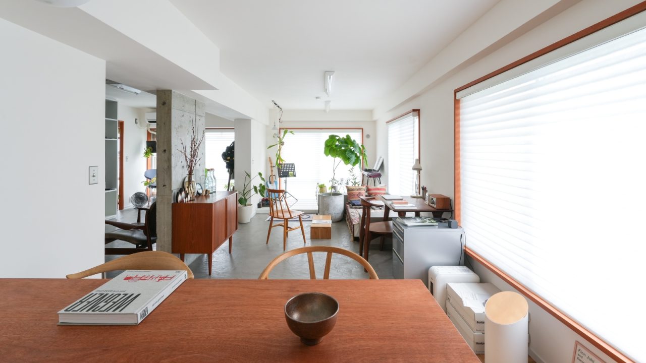 キッチンと壁を隔てて裏側、こもった位置にあるダイニングからリビングを望む。極力既存の間仕切り壁を除いたことにより、各室にあった窓がワンルームの中で連なる。ひと繋がりに見渡せる夜景も最高とのこと。