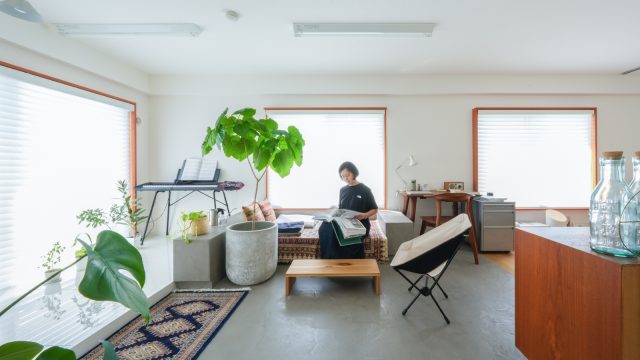 壁面収納の対面にあるリビング。床はモールテックスという左官材の塗り仕上げ。窓際には白い鏡面タイルで仕上げたオープンストレージを設け、趣味のピアノやギターのスペースに。日当たりもよく、観葉植物の居場所としても最適。