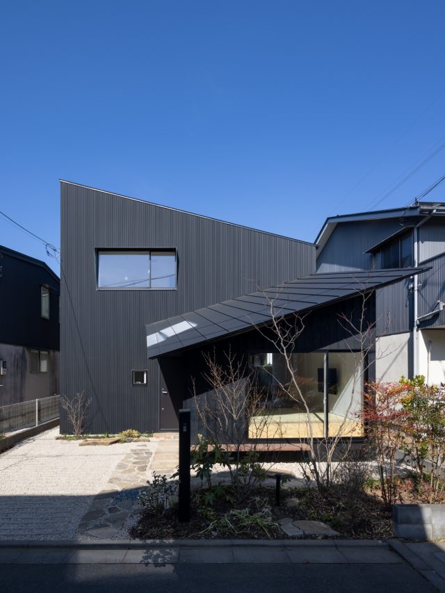 斜め屋根の下屋が特徴的な外観。黒い外壁に色とりどりの植栽が映えます。