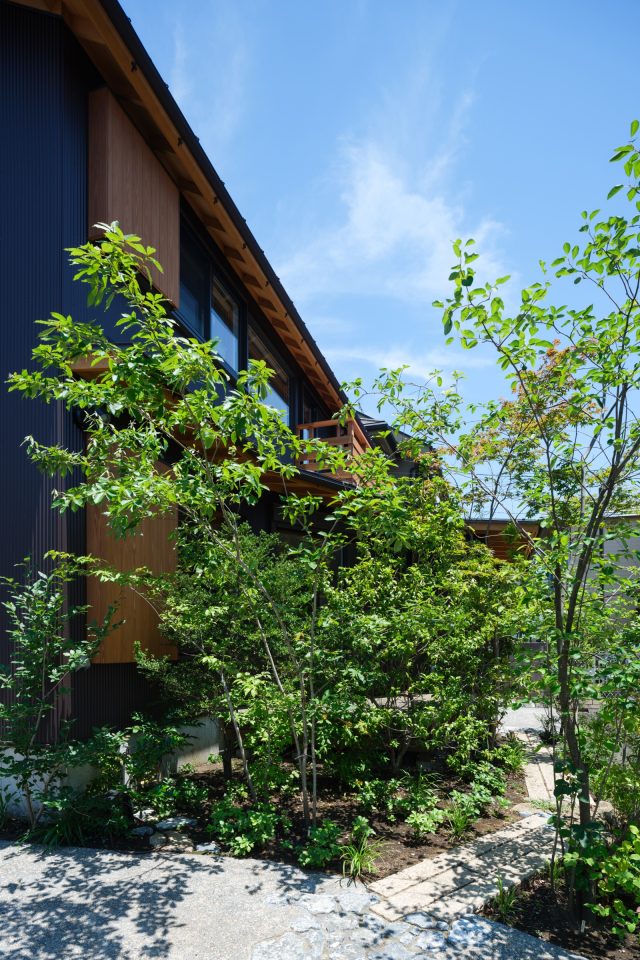 庭には小道が通り、外から見ると木々が層となりより濃く見えます。 木々のレイヤーによって塀がなくとも室内が見えにくくなっています。