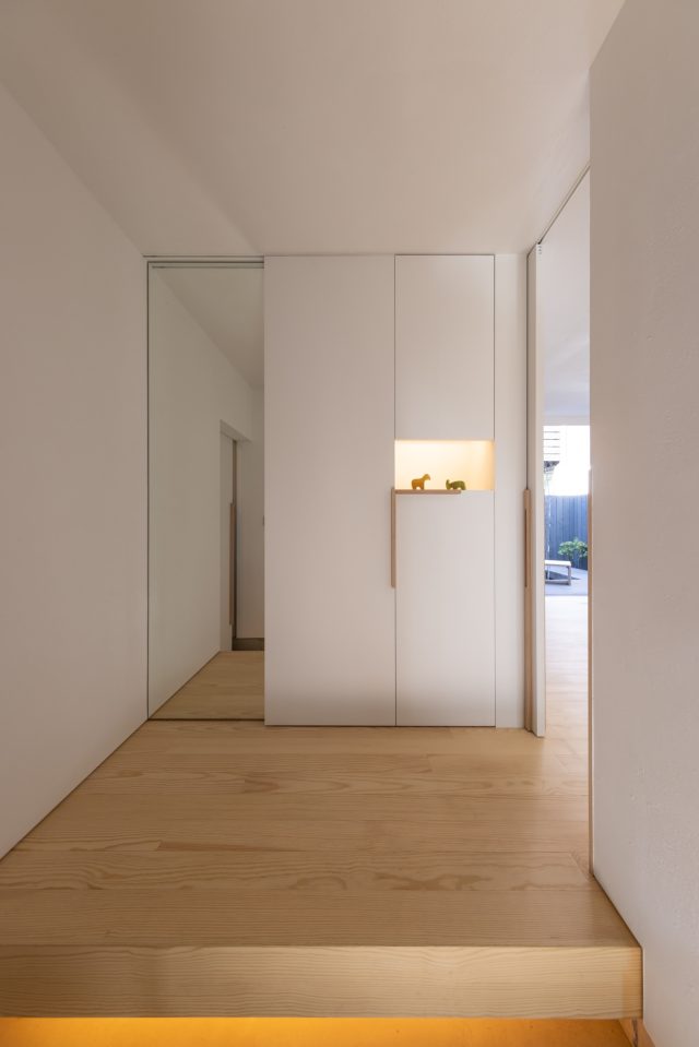 照明を飾り棚と足元の2箇所、最小限に抑えた玄関。逆さのL字取手は右が下駄箱、左の引き戸はトイレです。