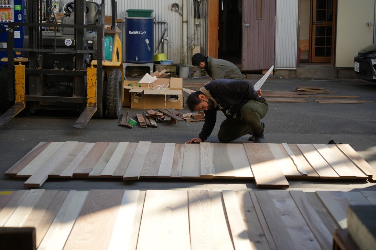 「日本の木」の壁面の樹種を並べて構成を確認する小泉さん
