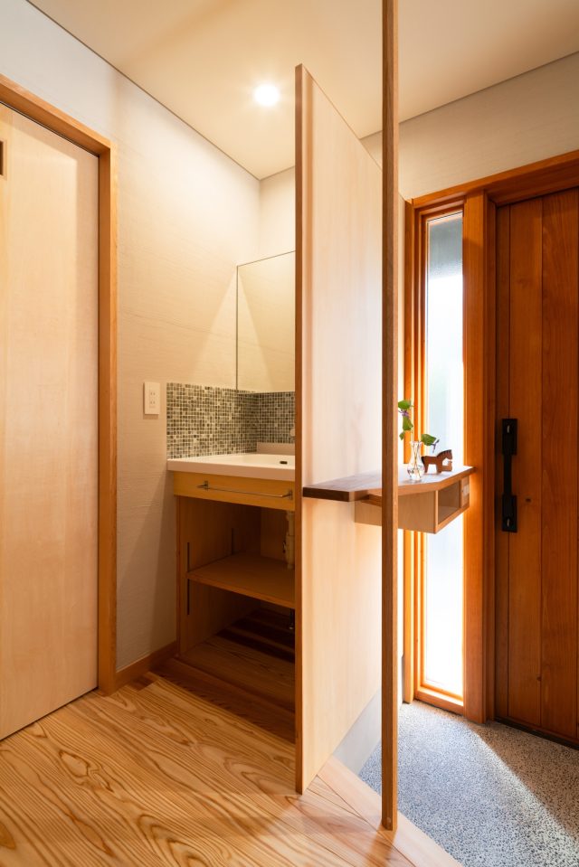 小さな棚と六角形の手すりがアクセントの玄関。脇の小さな洗面スペースは水回りが2階のため手洗いとして重宝しています