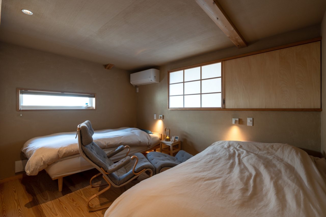 吹き抜けに面したご夫婦の寝室も静かな別荘のような雰囲気。室内窓は障子と木戸で光、熱を調節できるように