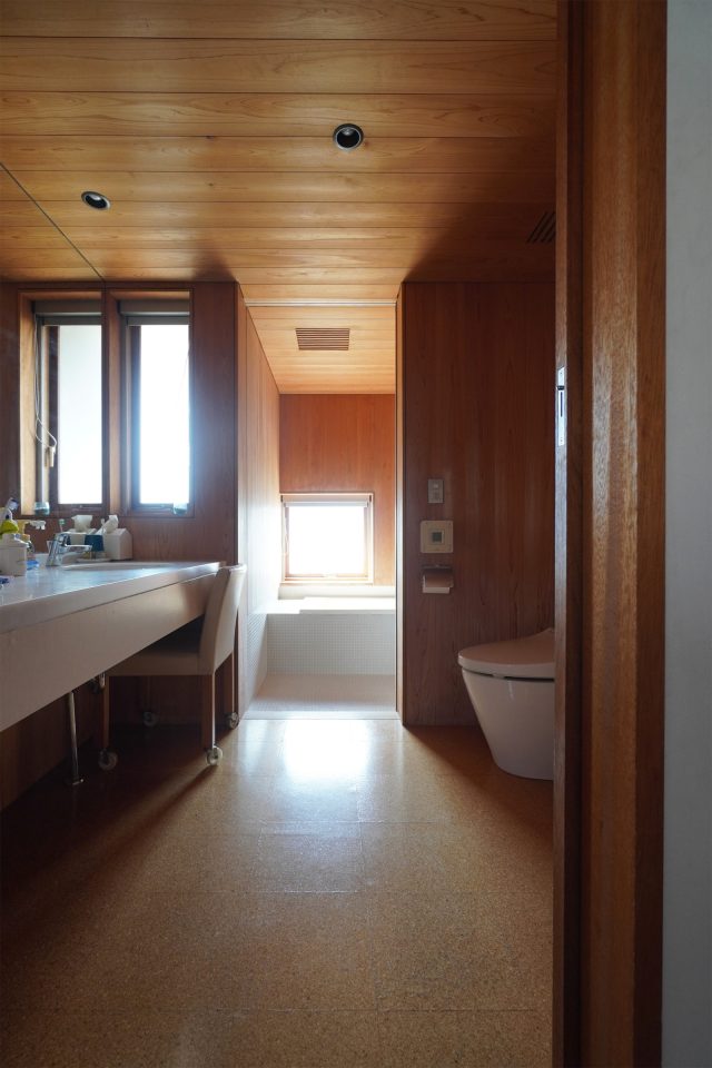 コルクタイルが敷かれた洗面脱衣所。奥にはサワラとタイル張りの浴室。