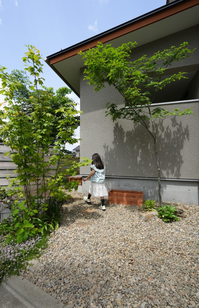 玄関前のポーチから小さな飛び石が庭にいざなう