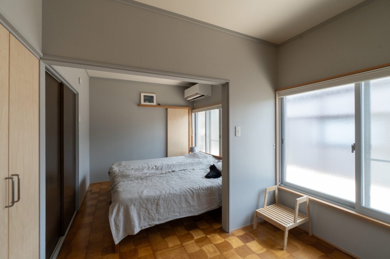 壁はグレーで統一し、レトロな風合いの既存の床を活かした寝室