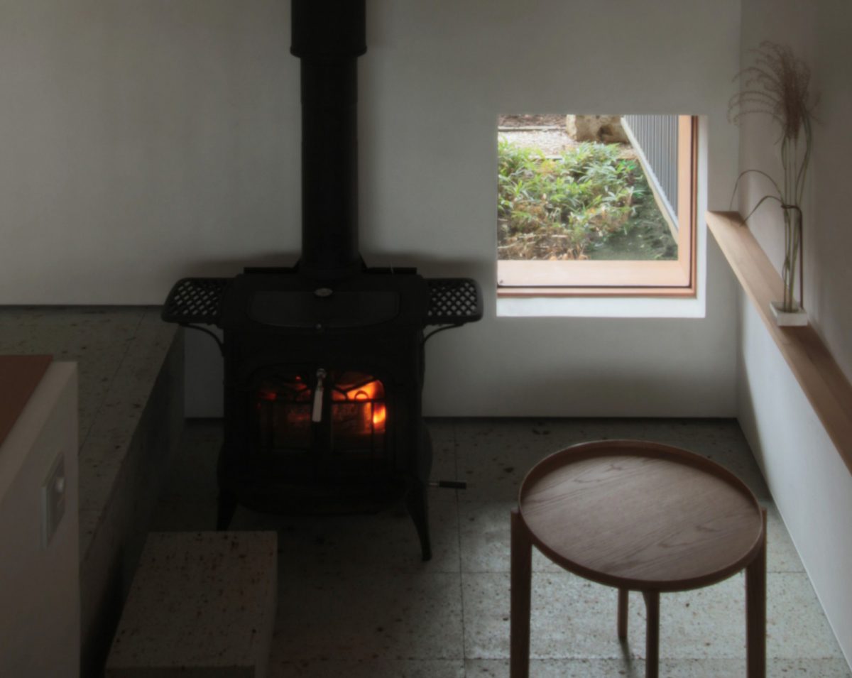 市中山居（しちゅうさんきょ）: リビングから少し掘り下げた土間スペース。ストーブの炎を眺めながらソファでくつろげる