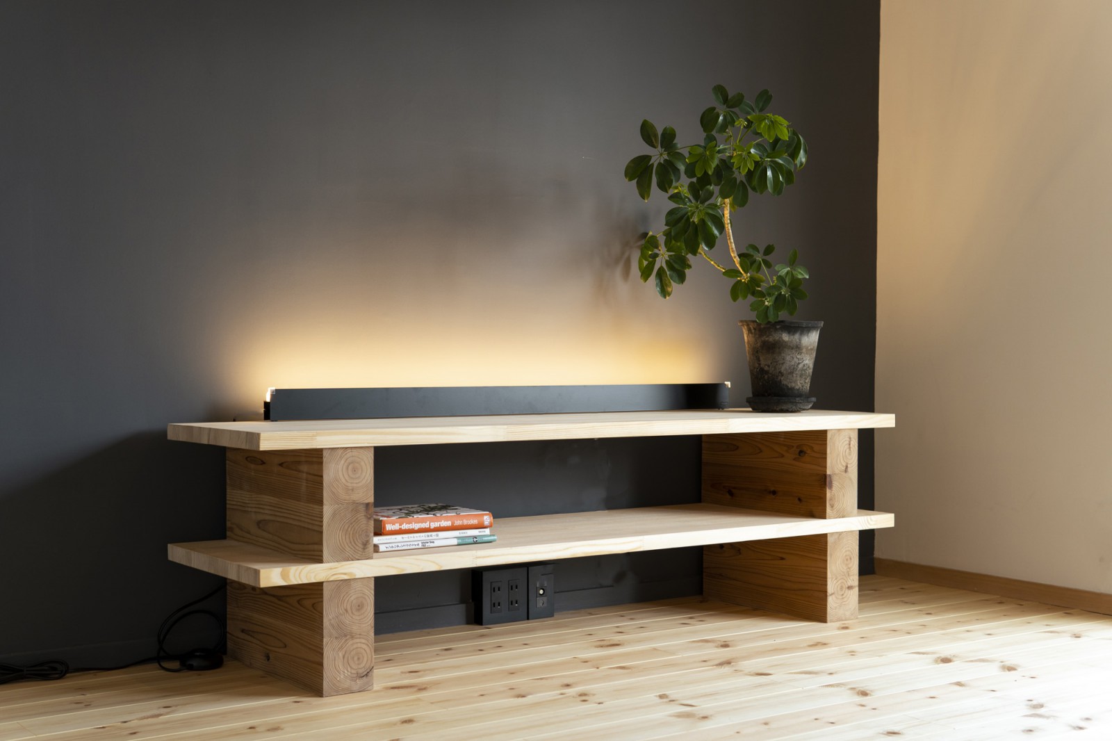 オリジナルのテレビボードは柱材と板材をシンプルに構成。目に優しい灯を配置し、アクセントウォールを強調。