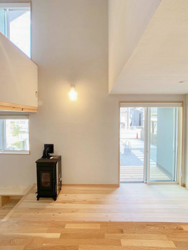 ダイニングとペレットストーブ。小さな吹き抜けを介して左側が中2階 その下がこもり感のあるくつろぎスペースです。
