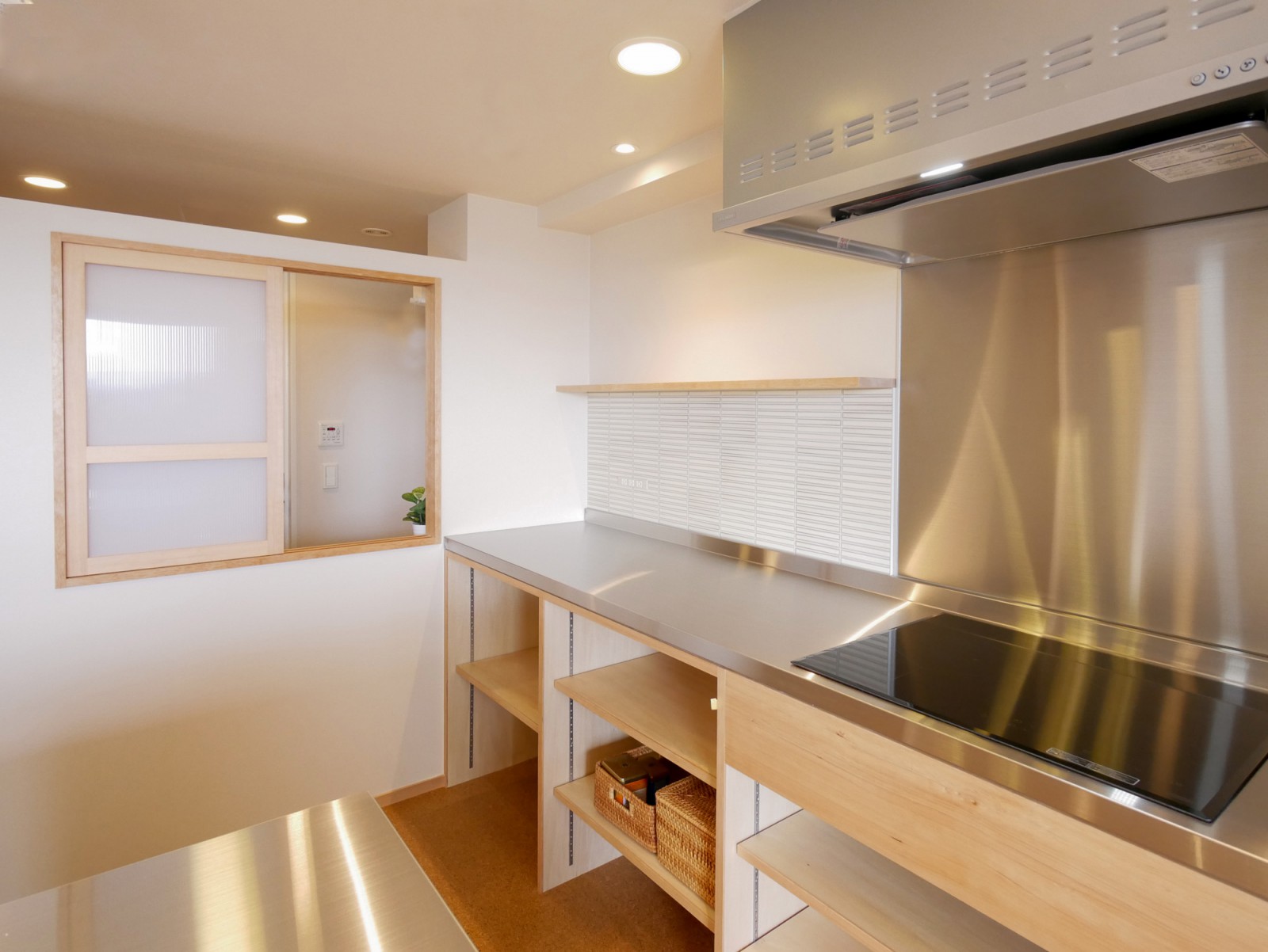 キッチンやカウンターは造作で製作。キッチンと脱衣所の間に室内窓を設けたことで光や風が室内に気持ちよく抜ける空間となっています。